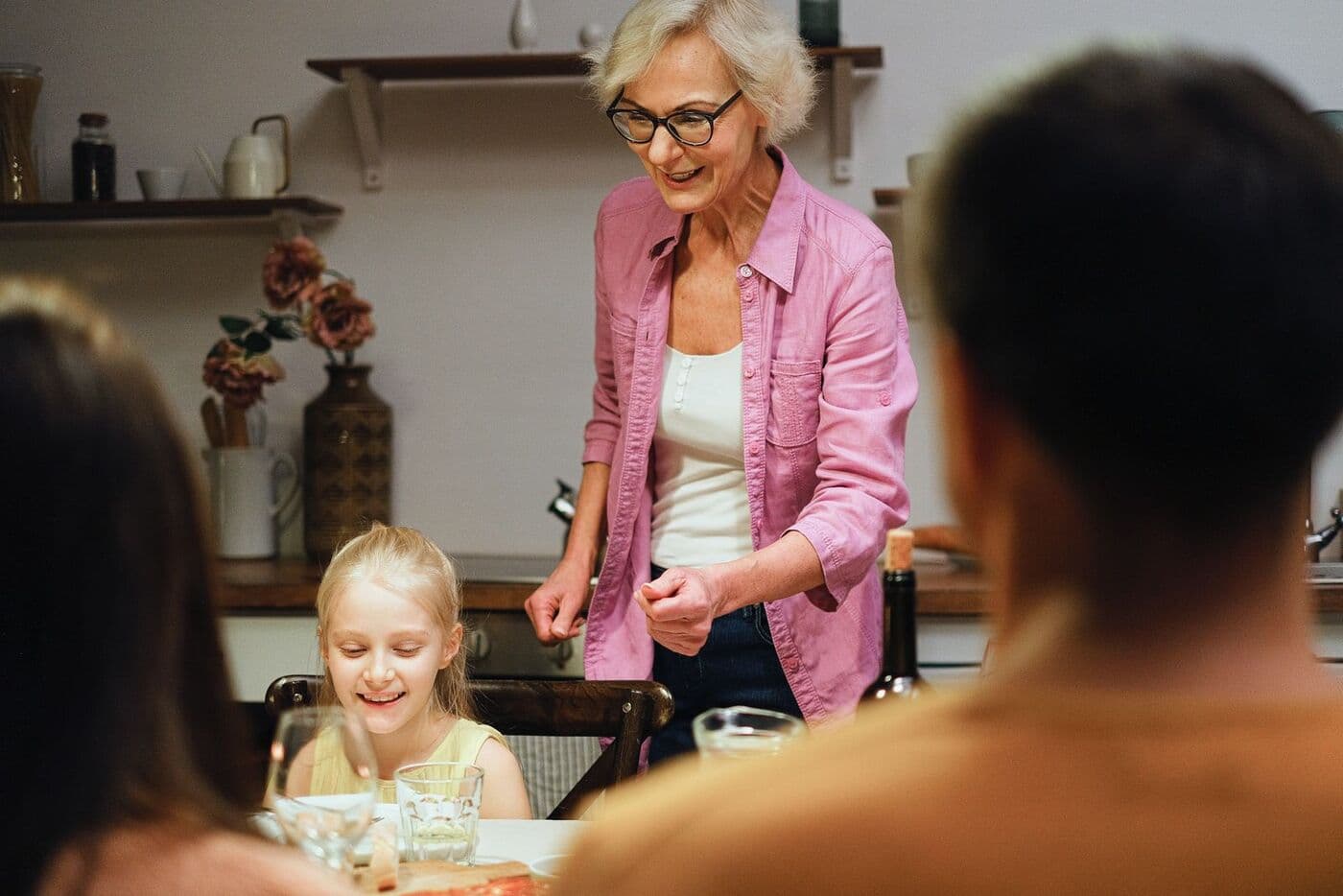 Grandmother laughing with family at the dinner table
