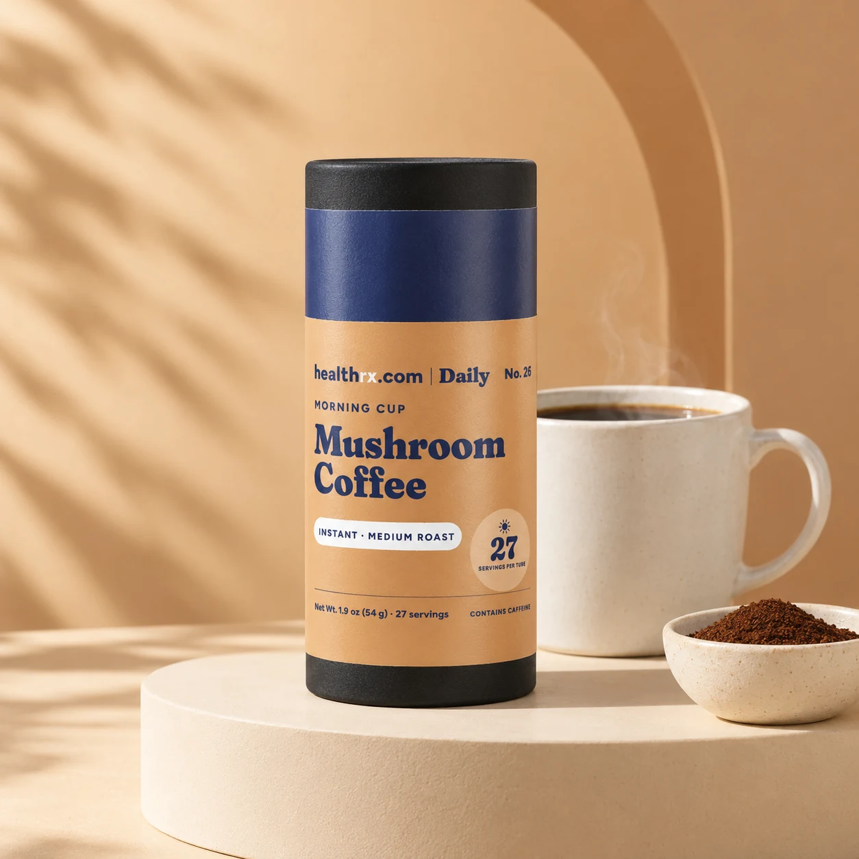 A tube of HealthRX.com Daily Mushroom Coffee, black cap and navy band, on a cream pedestal beside a mug of coffee